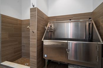 a large stainless steel tub in a bathroom with wooden walls and a shower